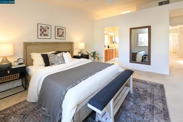 bedroom featuring ensuite bathroom, ceiling fan, and dark colored carpet