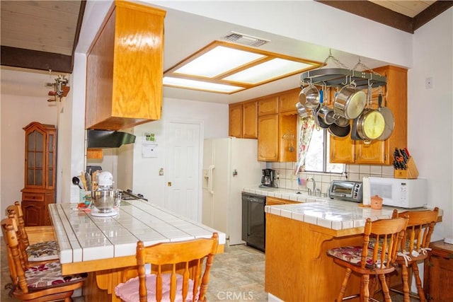 kitchen featuring tile countertops, kitchen peninsula, white appliances, decorative backsplash, and a breakfast bar