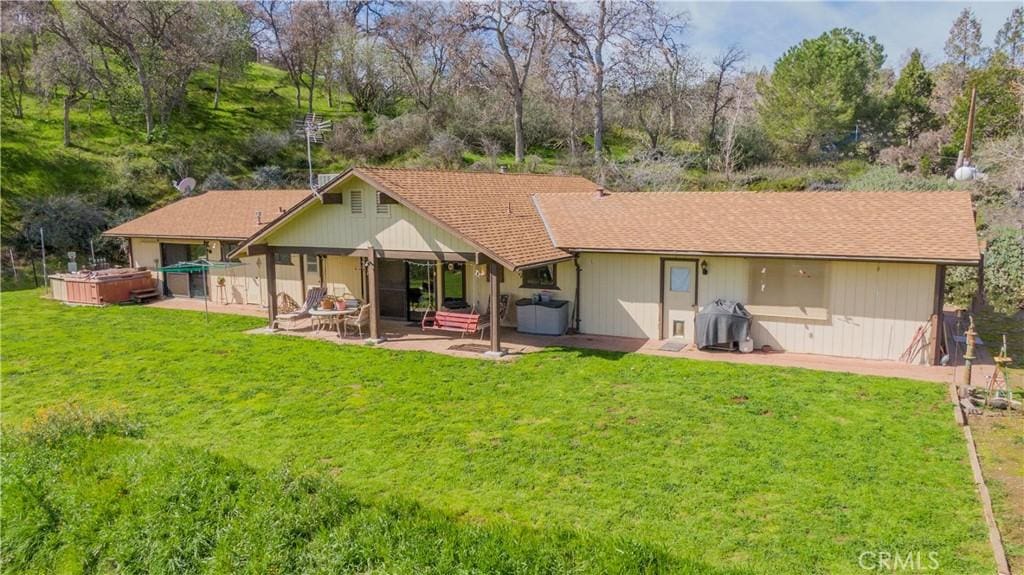 back of house with a yard, a hot tub, and a patio area