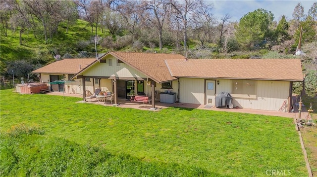 back of house with a yard, a hot tub, and a patio area