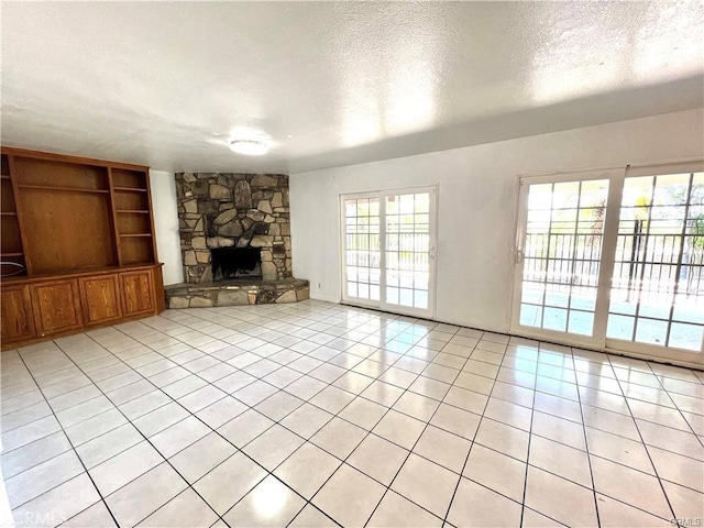 unfurnished living room with a fireplace, light tile patterned floors, a textured ceiling, and a healthy amount of sunlight