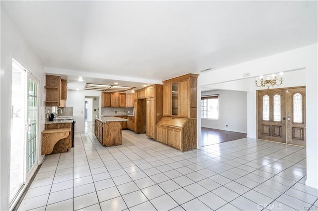 kitchen with a chandelier, light tile patterned floors, backsplash, and sink