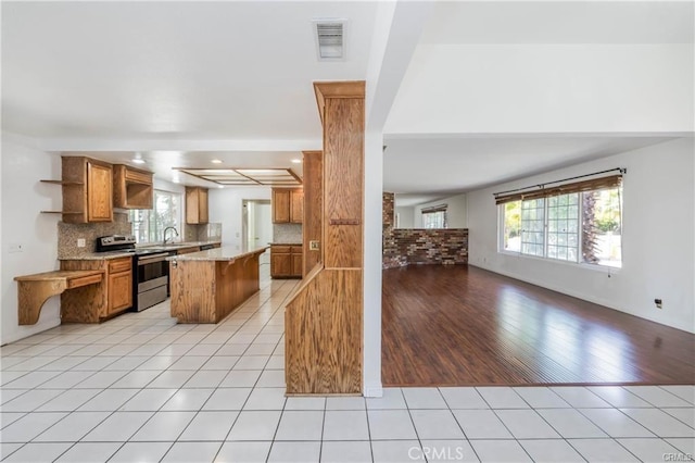 kitchen with stainless steel electric range, light hardwood / wood-style floors, a healthy amount of sunlight, and sink