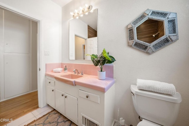 bathroom with hardwood / wood-style floors, decorative backsplash, toilet, and vanity