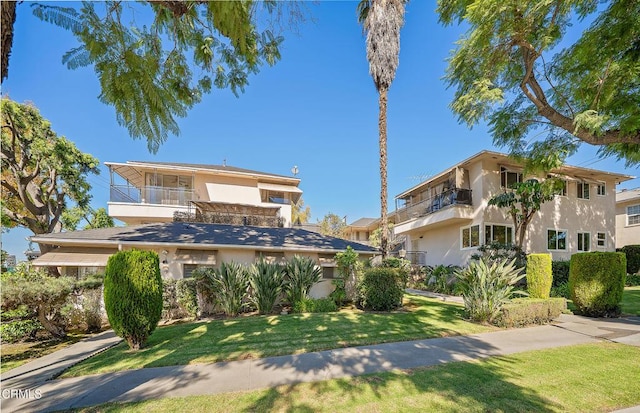 view of front of property featuring a balcony and a front yard