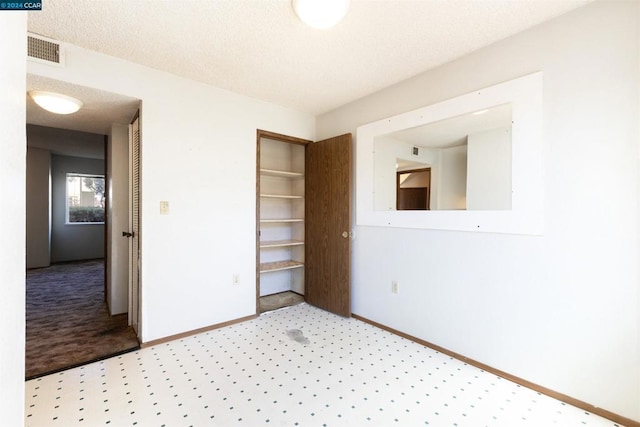 unfurnished bedroom featuring a textured ceiling and a closet