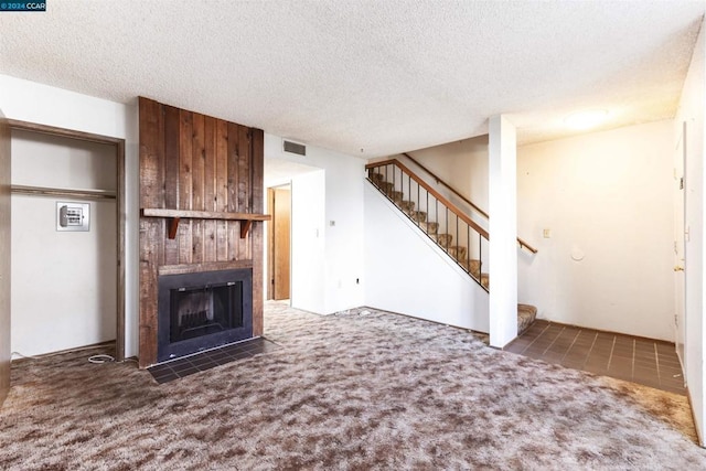 unfurnished living room with dark colored carpet, a textured ceiling, and a tiled fireplace