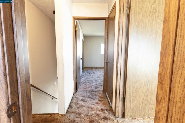 corridor featuring a textured ceiling and carpet floors