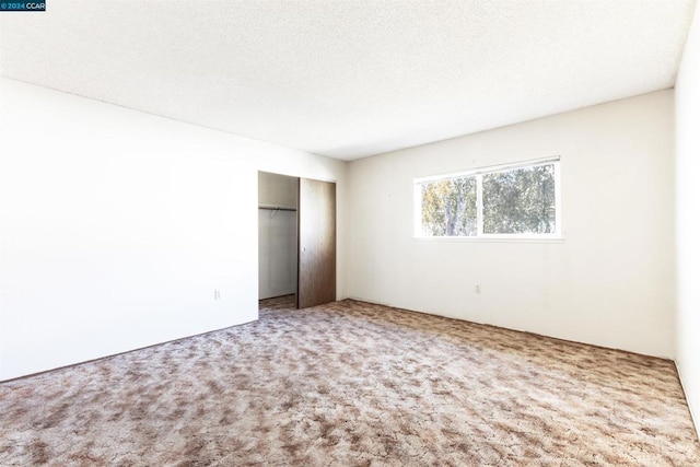 unfurnished bedroom with carpet, a textured ceiling, and a closet