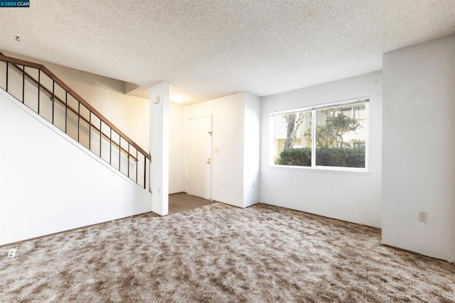 unfurnished living room featuring carpet and a textured ceiling