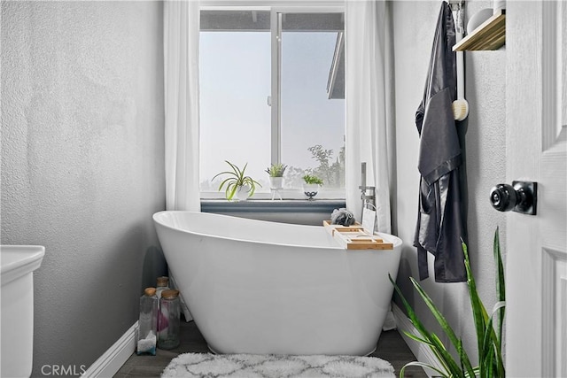 2052 Thomas Pl, West Covina, CA 91792 - bathroom with baseboards, a freestanding tub, a textured wall, wood finished floors, and toilet