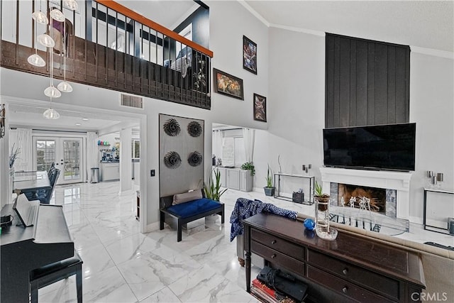 living room featuring french doors, a towering ceiling, and ornamental molding