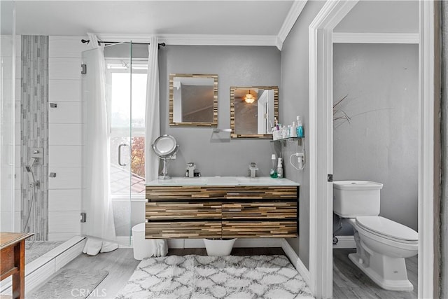 bathroom with hardwood / wood-style floors, vanity, toilet, ornamental molding, and a shower with shower door