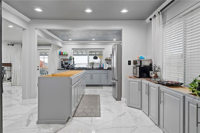 kitchen featuring gray cabinetry, crown molding, sink, stainless steel refrigerator, and butcher block counters