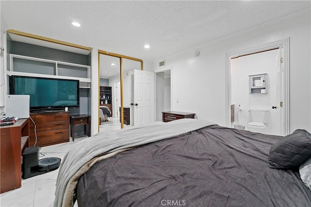 bedroom featuring ensuite bathroom and a textured ceiling