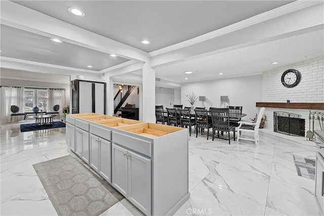 kitchen with a kitchen island, ornamental molding, and a brick fireplace