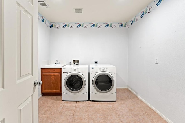 washroom with cabinets, light tile patterned floors, sink, and washing machine and clothes dryer