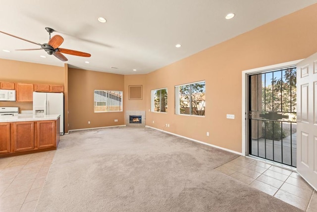 unfurnished living room featuring a fireplace, light colored carpet, and ceiling fan