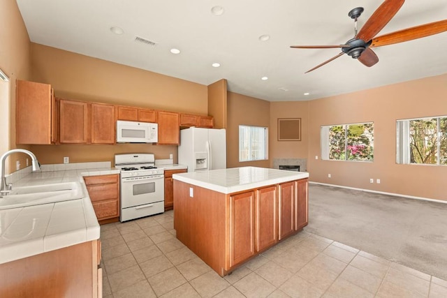 kitchen with ceiling fan, sink, white appliances, light carpet, and a kitchen island