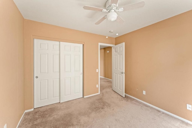 unfurnished bedroom featuring ceiling fan, a closet, and light colored carpet