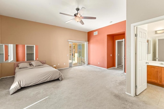 bedroom with ceiling fan, light colored carpet, and ensuite bath