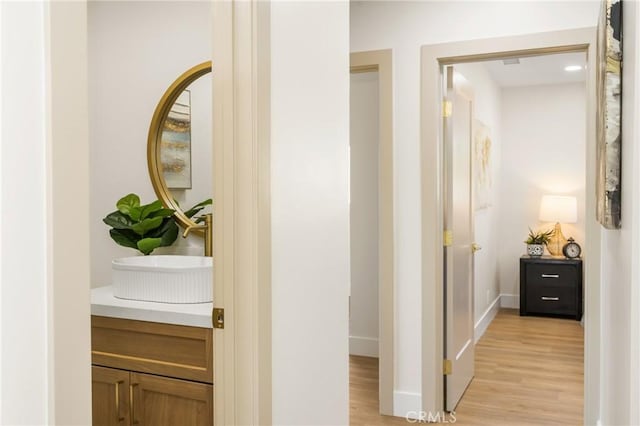 hallway with sink and light hardwood / wood-style floors