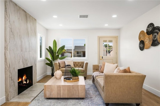 living area with a high end fireplace and light hardwood / wood-style floors