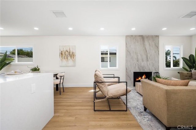 living room with a wealth of natural light, a fireplace, and light hardwood / wood-style floors