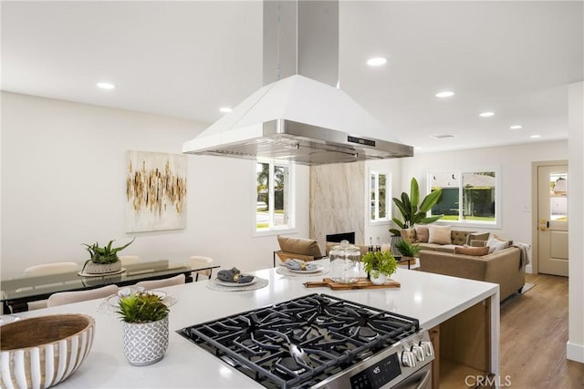 kitchen with stainless steel gas stove, island range hood, and wood-type flooring