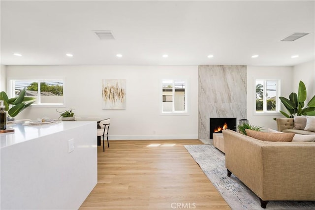 living room featuring a high end fireplace and light hardwood / wood-style flooring