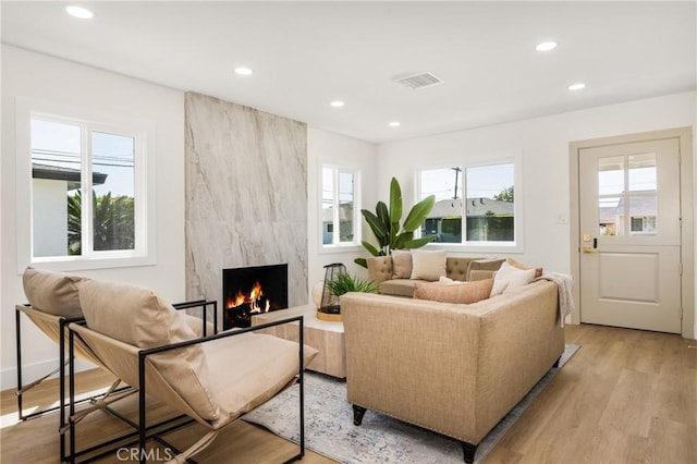 living room with a high end fireplace and light hardwood / wood-style flooring