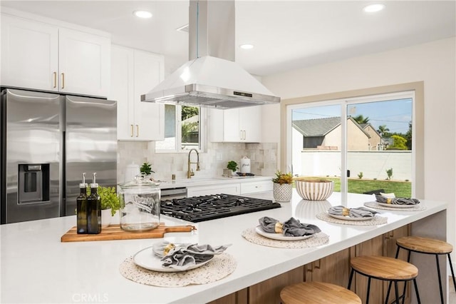 kitchen featuring stainless steel fridge with ice dispenser, island range hood, a kitchen breakfast bar, and white cabinets