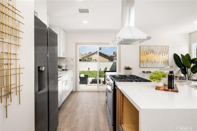 kitchen with a healthy amount of sunlight, stainless steel appliances, white cabinets, and island exhaust hood