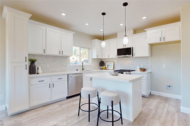 kitchen with white cabinets, appliances with stainless steel finishes, a center island, and backsplash