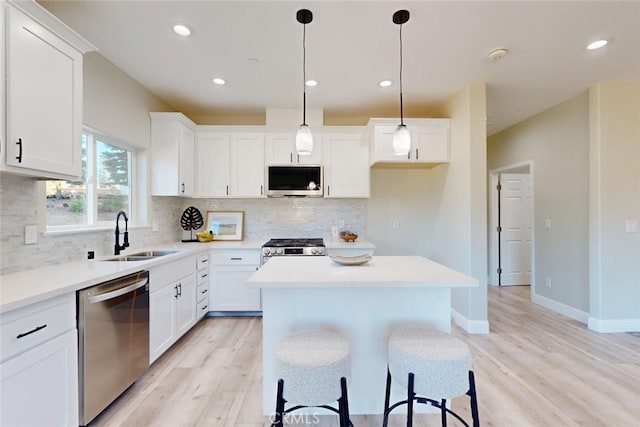 kitchen with white cabinetry, hanging light fixtures, and appliances with stainless steel finishes