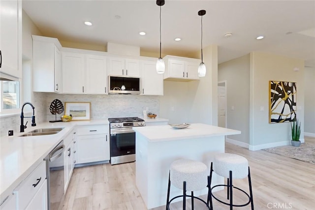 kitchen with sink, white cabinetry, stainless steel appliances, and light wood-type flooring