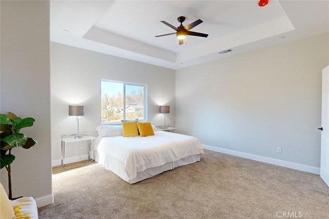 bedroom with light carpet, a raised ceiling, and ceiling fan