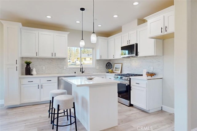 kitchen with white cabinets, a kitchen island, light hardwood / wood-style floors, and stainless steel appliances