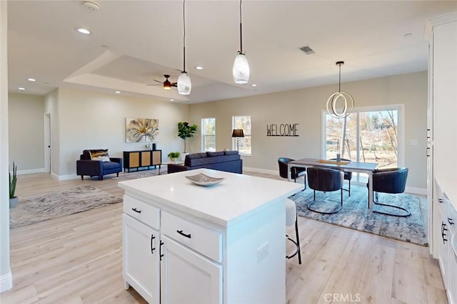 kitchen featuring light hardwood / wood-style floors, decorative light fixtures, ceiling fan, and white cabinetry