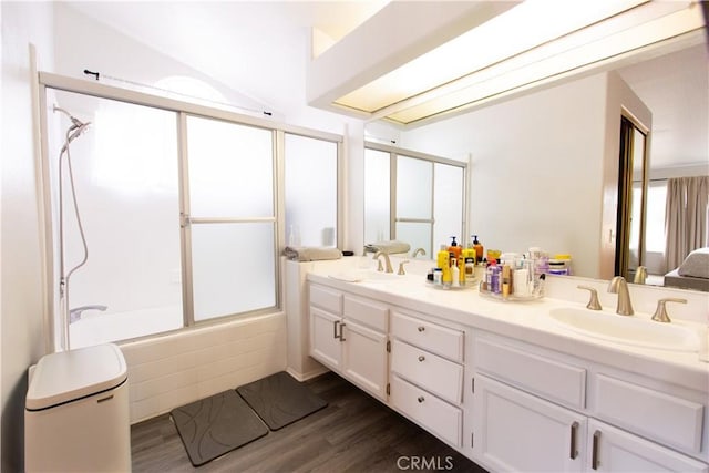 bathroom featuring vanity, hardwood / wood-style flooring, and bath / shower combo with glass door