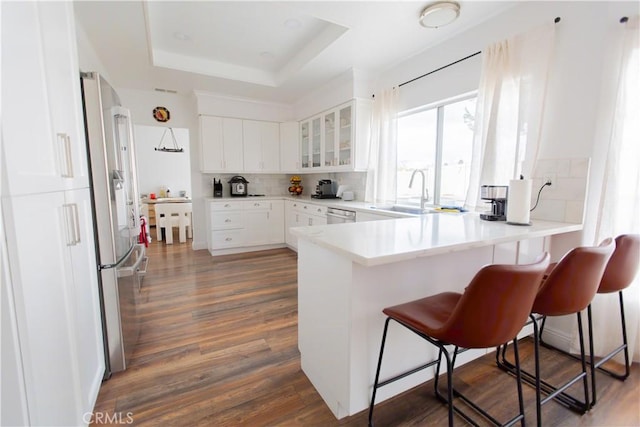 kitchen with white cabinetry, a breakfast bar area, a raised ceiling, and appliances with stainless steel finishes