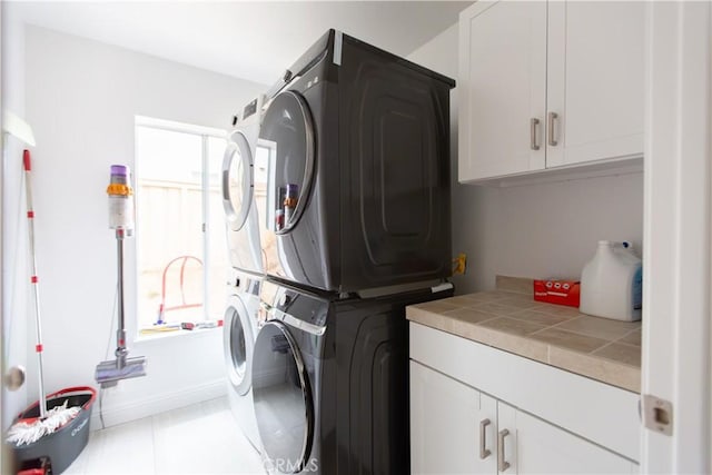 washroom with cabinets and stacked washer and clothes dryer