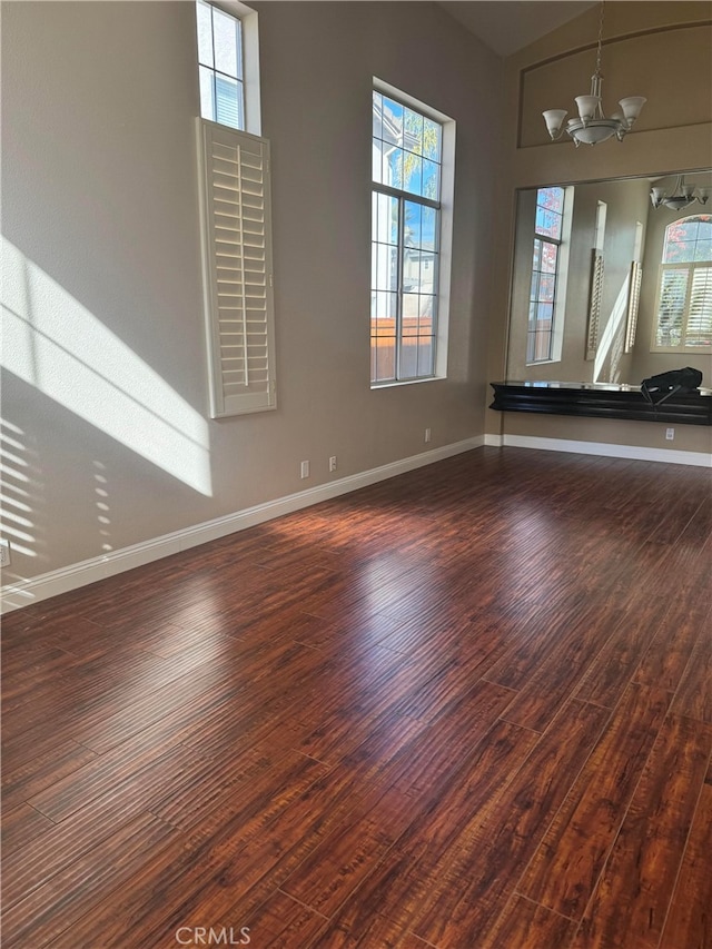 empty room with dark hardwood / wood-style flooring and an inviting chandelier