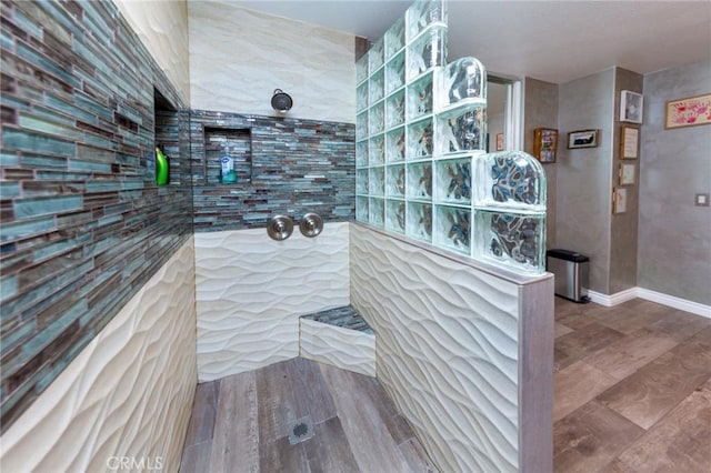 bathroom with a tile shower and hardwood / wood-style floors