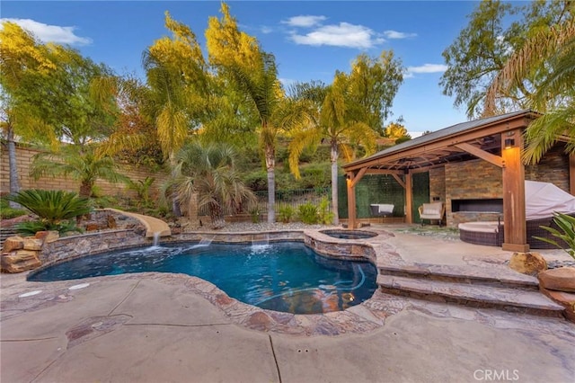 view of pool featuring a patio, a gazebo, an in ground hot tub, a water slide, and a fireplace