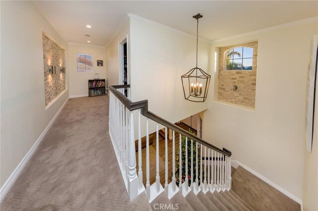 hall with a chandelier, crown molding, and carpet floors