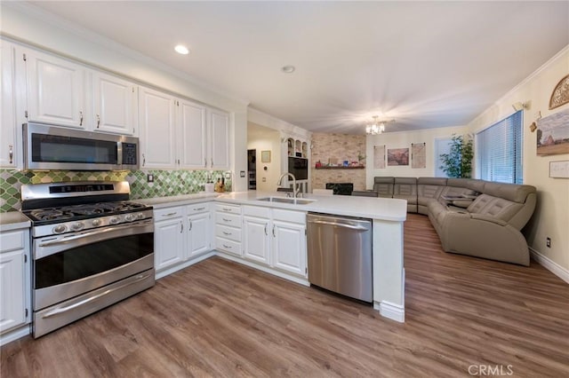 kitchen with stainless steel appliances, white cabinets, crown molding, sink, and kitchen peninsula