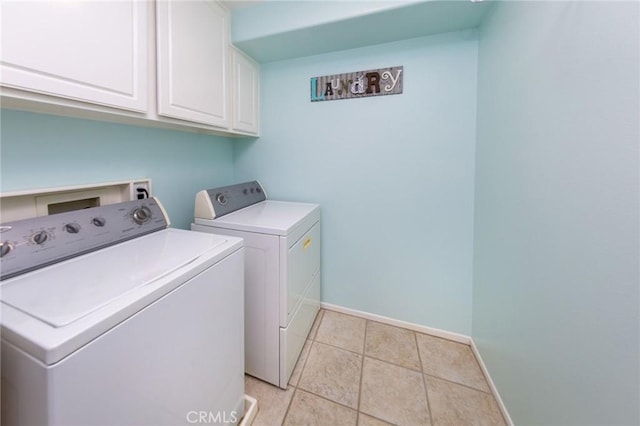 laundry area featuring washing machine and dryer, light tile patterned floors, and cabinets