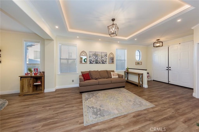 living room with ornamental molding, dark wood-type flooring, a healthy amount of sunlight, and a raised ceiling