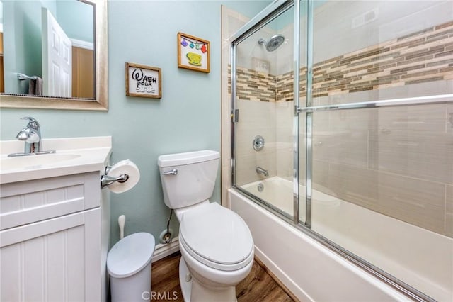 full bathroom with hardwood / wood-style floors, toilet, combined bath / shower with glass door, and vanity